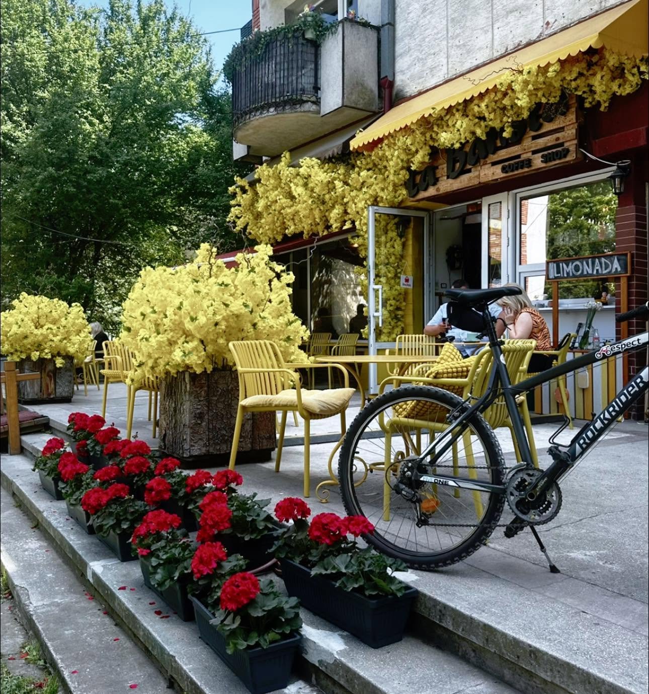 Intrarea cafenelei La Barista și terasa cu scaune galbene