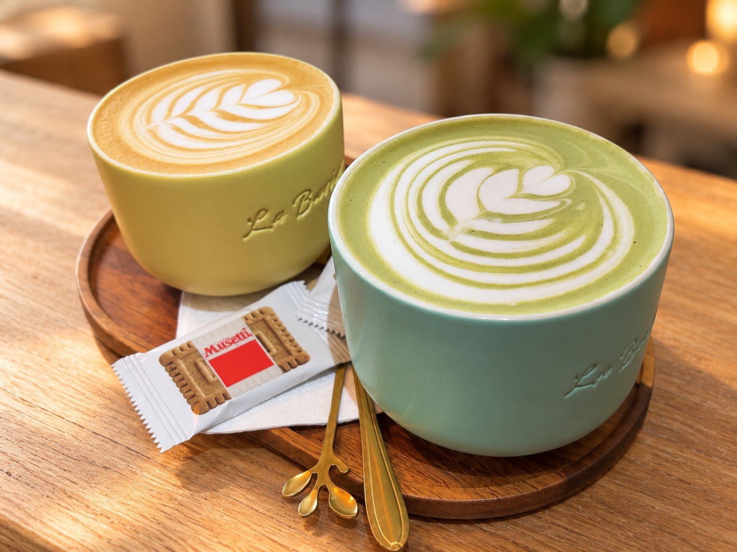 Matcha Latte în ceașcă verde, alături de o cafea cu latte art, la La Barista